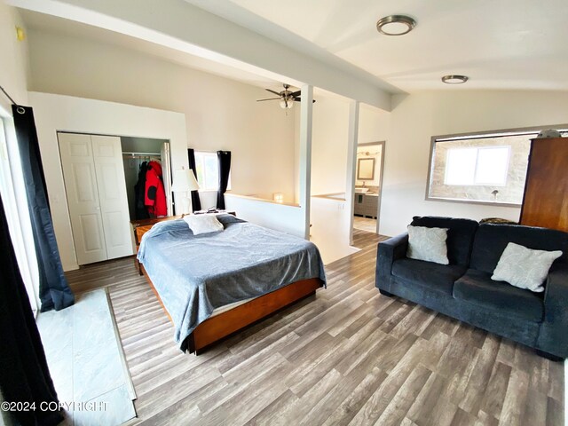 bedroom with lofted ceiling with beams, hardwood / wood-style floors, and a closet