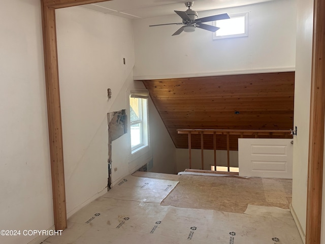 interior space featuring lofted ceiling, wood walls, and ceiling fan