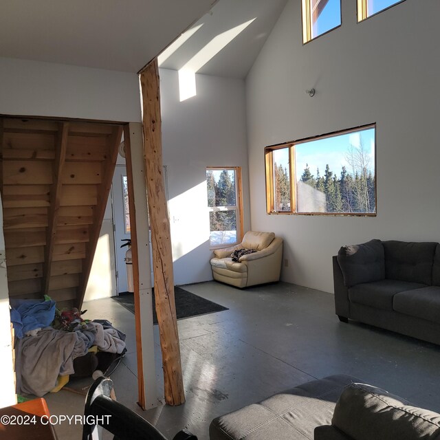 living room with plenty of natural light, concrete floors, and high vaulted ceiling