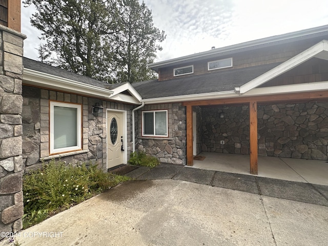 exterior space featuring stone siding, a shingled roof, and an attached carport