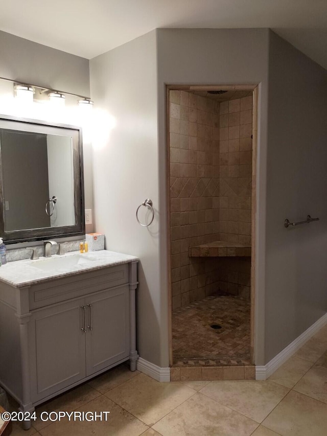 bathroom with vanity, baseboards, tiled shower, and tile patterned floors