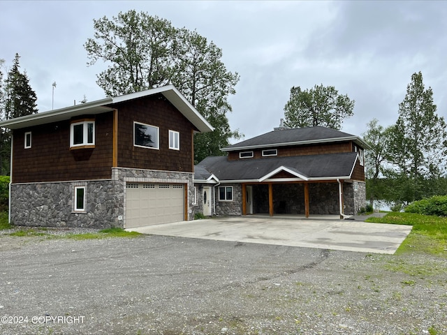 view of front of home featuring driveway, stone siding, and an attached garage