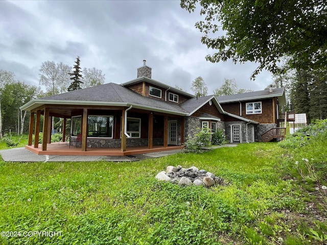 rear view of property featuring stone siding, a yard, and a chimney