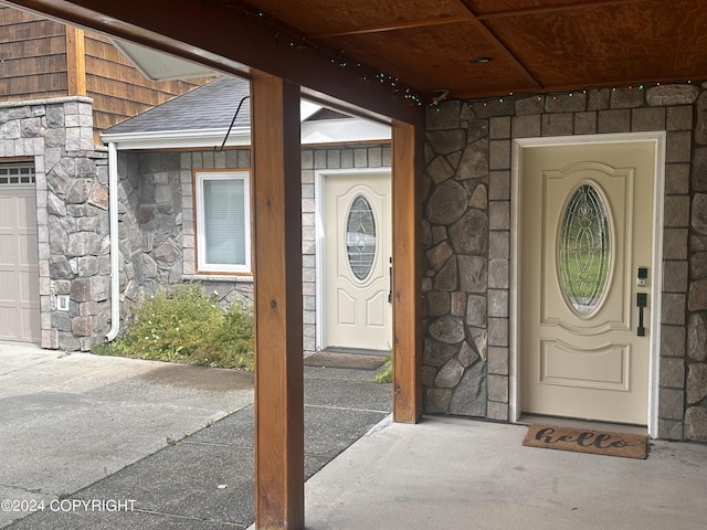 doorway to property featuring a shingled roof and stone siding