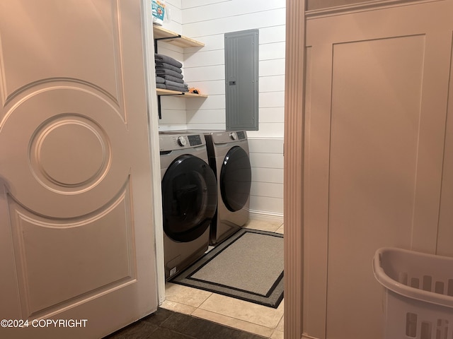 washroom with laundry area, wood walls, dark tile patterned floors, washer and dryer, and electric panel