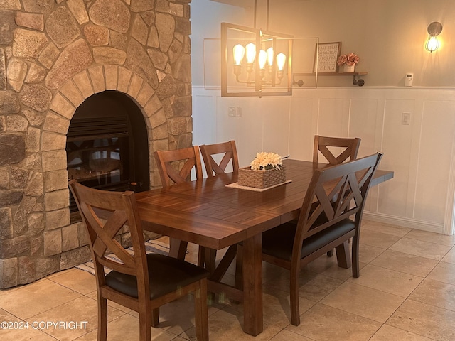 dining area featuring wainscoting, a decorative wall, an inviting chandelier, and light tile patterned floors