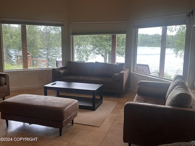 living room with light tile patterned floors, a water view, and a healthy amount of sunlight