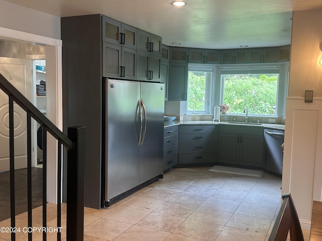 kitchen featuring light tile patterned floors, glass insert cabinets, appliances with stainless steel finishes, a sink, and recessed lighting