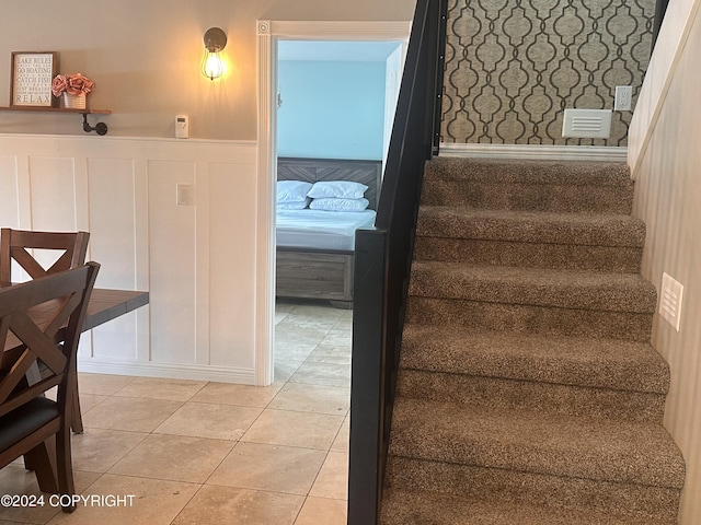 stairs with a wainscoted wall, tile patterned flooring, and a decorative wall