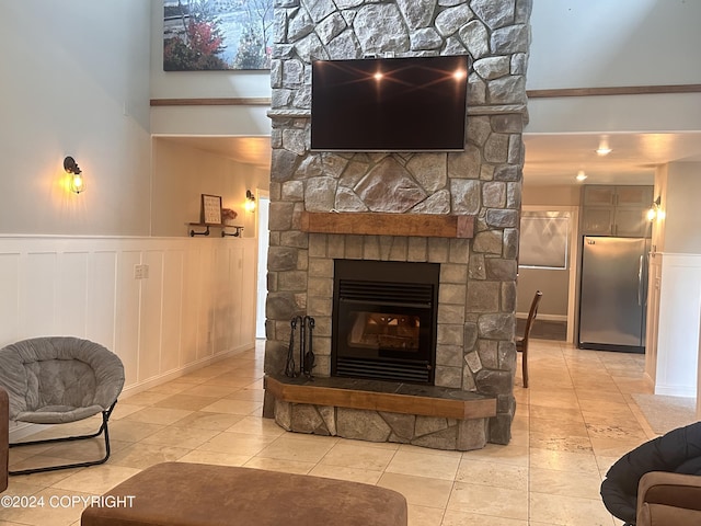 living room with wainscoting, a fireplace, a high ceiling, and light tile patterned floors