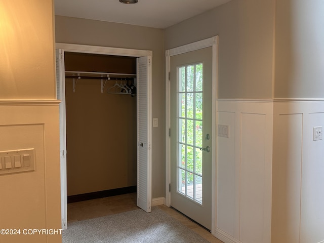 doorway to outside with wainscoting, plenty of natural light, and a decorative wall