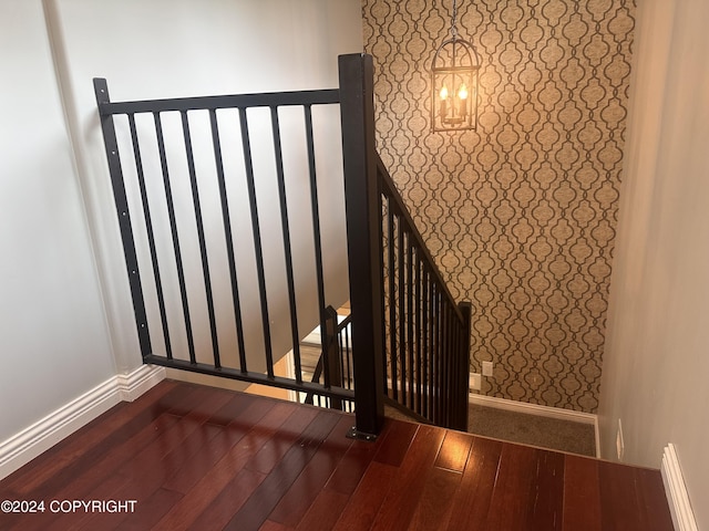 staircase with baseboards, wood-type flooring, and wallpapered walls