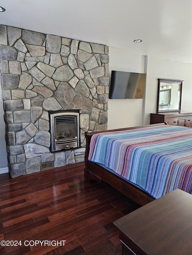 bedroom featuring visible vents, a stone fireplace, and wood finished floors