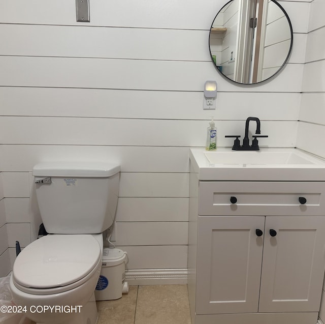 half bathroom with tile patterned flooring, vanity, and toilet