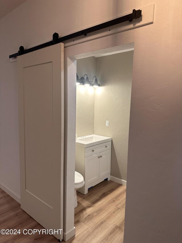 bathroom with baseboards, a textured wall, toilet, wood finished floors, and vanity