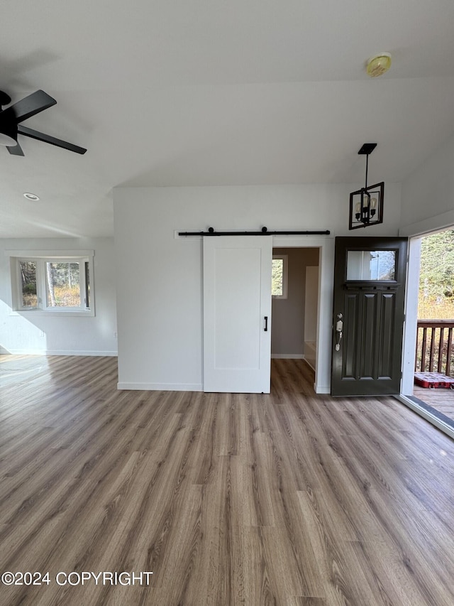 unfurnished living room featuring a barn door, baseboards, and wood finished floors