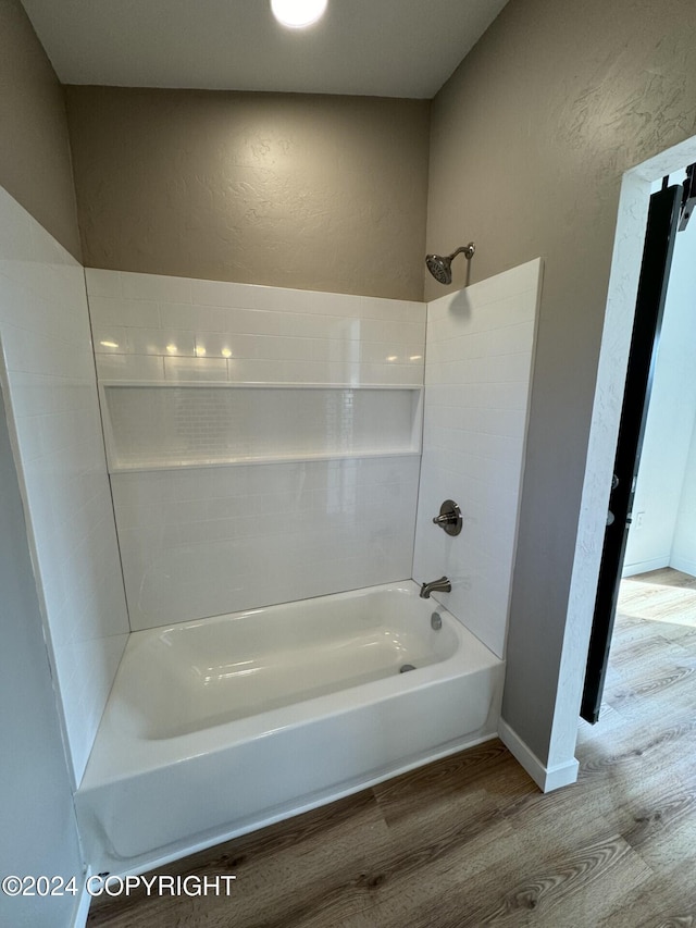 full bathroom with bathtub / shower combination, a textured wall, baseboards, and wood finished floors