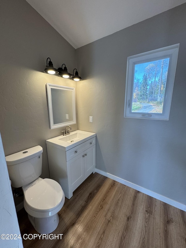 half bath featuring vanity, wood finished floors, toilet, and baseboards