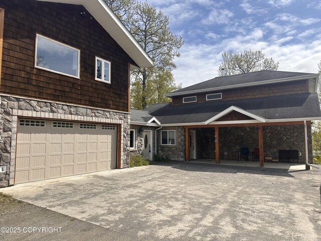 52305 Admiralty Dr, Nikiski/North Kenai, AK 99611 - view of front of home with stone siding, concrete driveway, and a garage