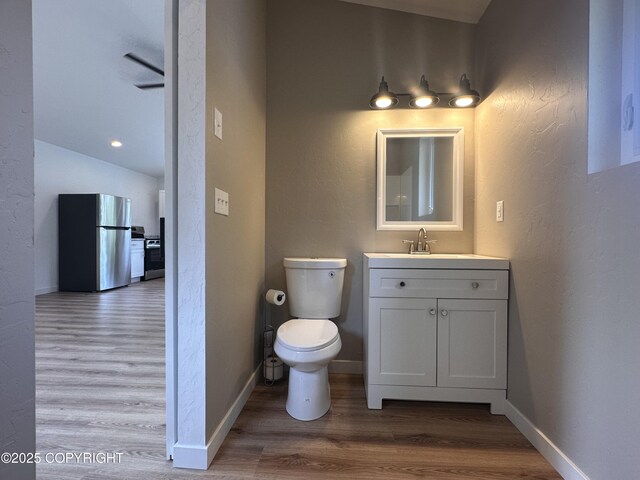 52305 Admiralty Dr, Nikiski/North Kenai, AK 99611 - bathroom with wood finished floors, toilet, vanity, a textured wall, and baseboards
