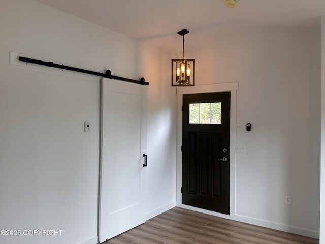 52305 Admiralty Dr, Nikiski/North Kenai, AK 99611 - entryway featuring a barn door, wood finished floors, a chandelier, and baseboards