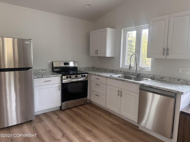 52305 Admiralty Dr, Nikiski/North Kenai, AK 99611 - kitchen featuring stainless steel appliances, a sink, white cabinets, and vaulted ceiling