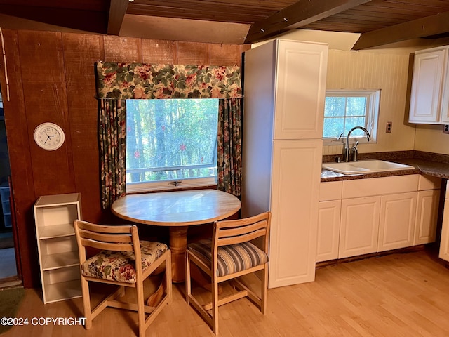 dining room featuring wooden ceiling, light hardwood / wood-style flooring, sink, and beam ceiling