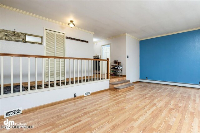 empty room featuring light wood-type flooring and ornamental molding