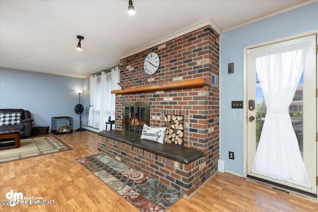 living room featuring a brick fireplace, light wood-type flooring, and crown molding