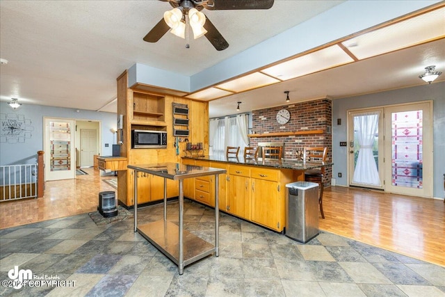 kitchen with wood-type flooring, a textured ceiling, kitchen peninsula, and ceiling fan