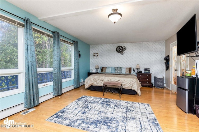 bedroom with wood-type flooring, baseboard heating, and stainless steel fridge