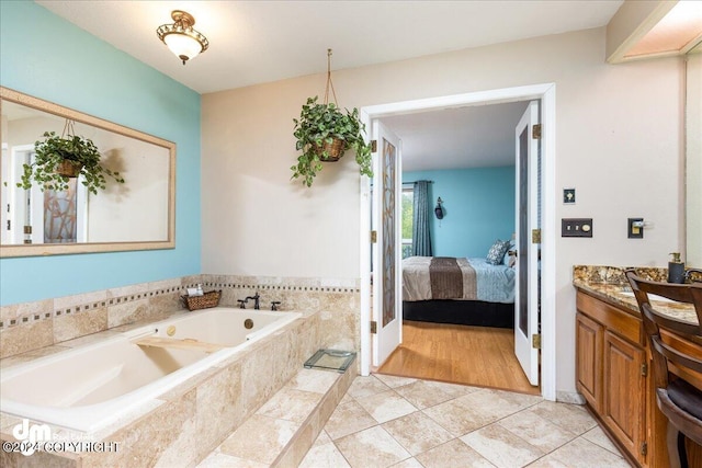 bathroom featuring wood-type flooring, a relaxing tiled tub, and vanity