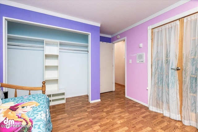 bedroom with wood-type flooring, ornamental molding, and a closet