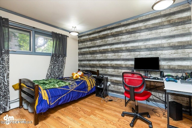 bedroom featuring hardwood / wood-style flooring, wooden walls, and baseboard heating