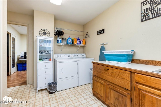 clothes washing area with light hardwood / wood-style floors and washing machine and clothes dryer