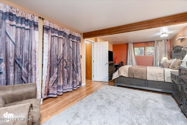 bedroom featuring beamed ceiling and light hardwood / wood-style floors