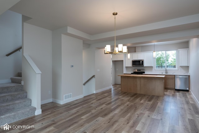 kitchen with open floor plan, stainless steel appliances, light wood-type flooring, and baseboards