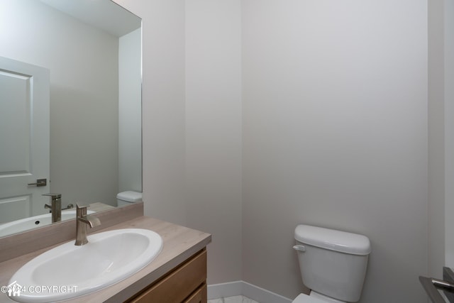 bathroom featuring baseboards, toilet, and vanity