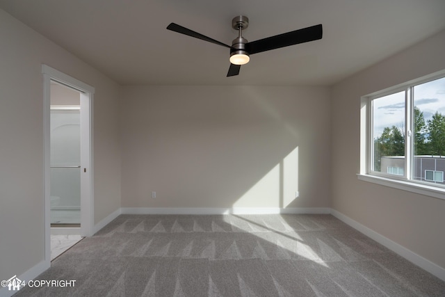 carpeted empty room with ceiling fan and baseboards