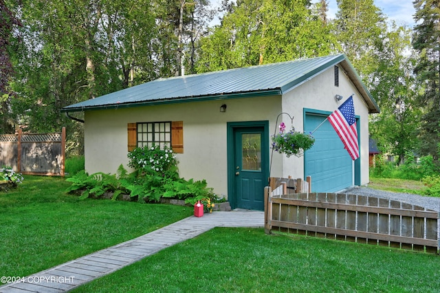 view of front of home featuring a garage, an outbuilding, and a front lawn