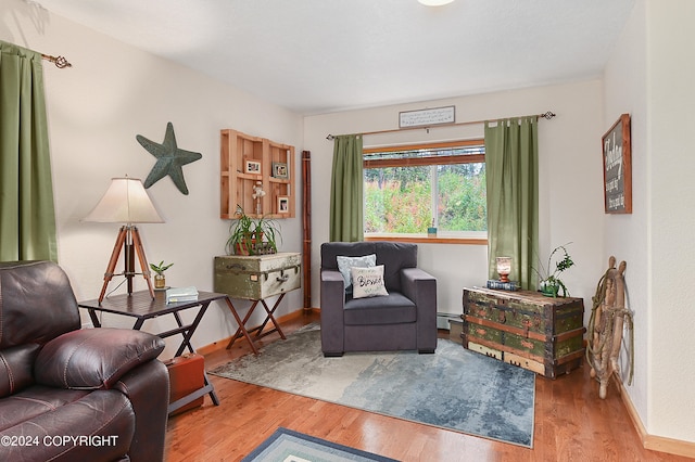 sitting room with hardwood / wood-style flooring and a baseboard heating unit