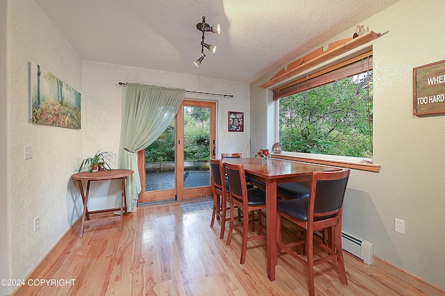 dining room with french doors, rail lighting, a textured ceiling, a baseboard heating unit, and light hardwood / wood-style flooring