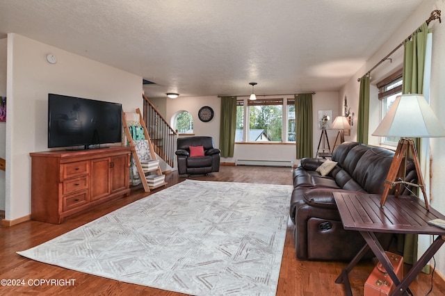 living room featuring a textured ceiling, light hardwood / wood-style flooring, and a baseboard heating unit