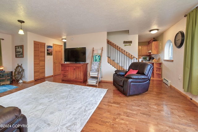 living room with a textured ceiling, a baseboard radiator, and light hardwood / wood-style flooring