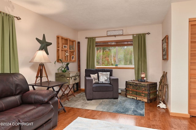 sitting room with a baseboard heating unit, a textured ceiling, and light wood-type flooring