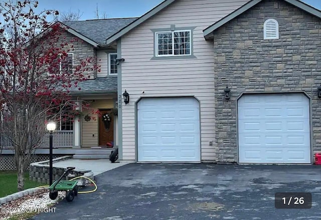 view of front of property featuring stone siding, driveway, a garage, and roof with shingles