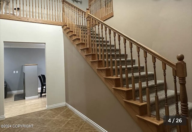 stairs with tile patterned flooring, a high ceiling, and baseboards