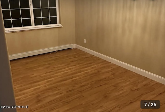 empty room with baseboards, baseboard heating, and wood finished floors