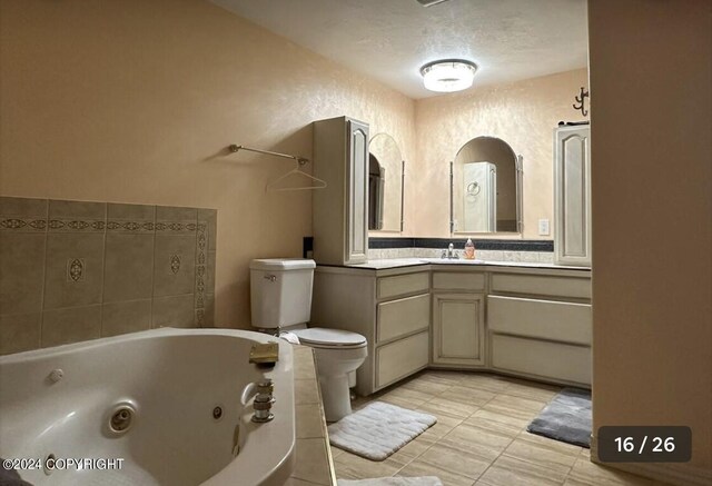 bathroom with toilet, tile patterned floors, vanity, a textured ceiling, and a bath