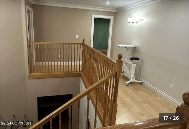 stairway with wood finished floors, baseboards, and ornamental molding